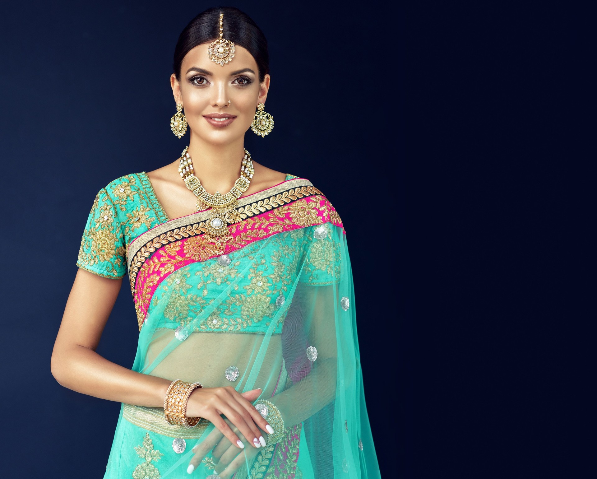 Portrait of beautiful girl dressed in a traditional indian national suit, jewelry set, blouse and shawl (dupatta).