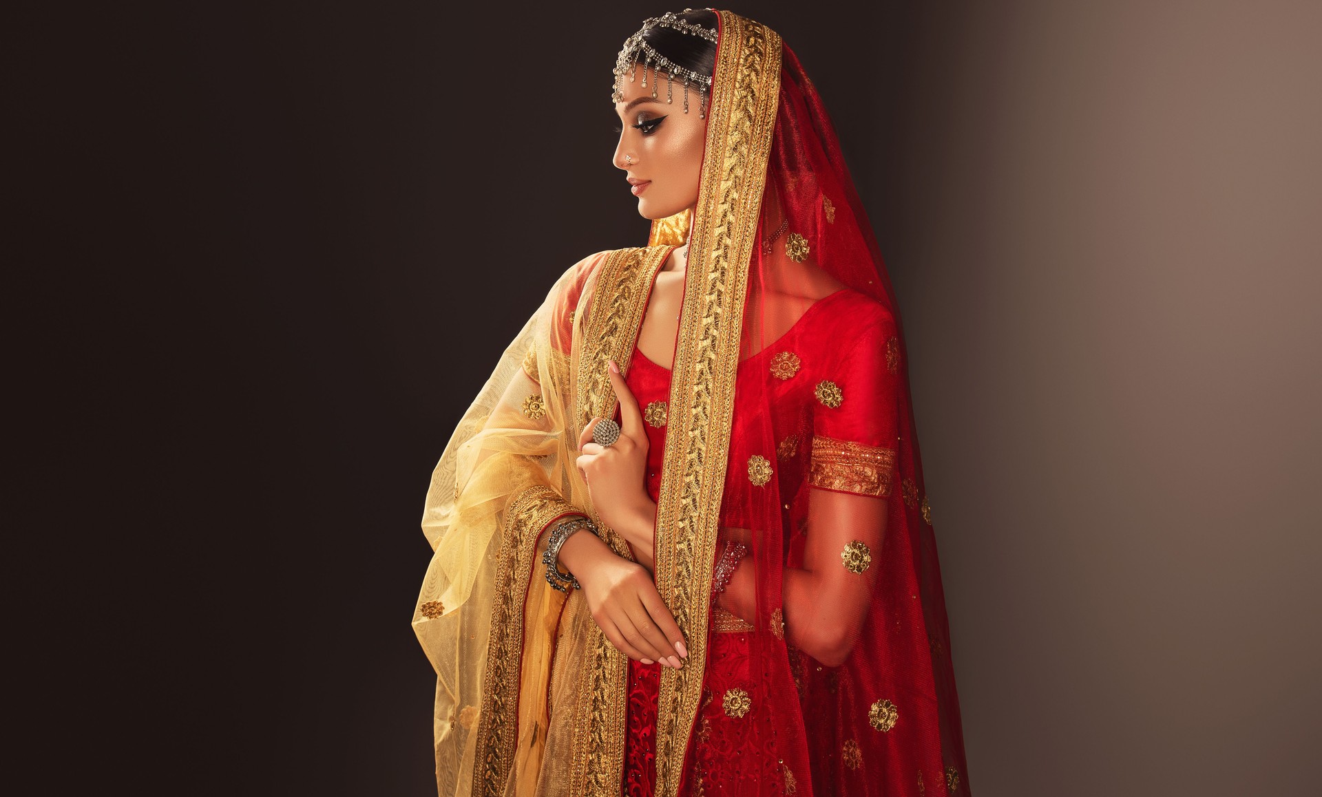 Young beautiful woman dressed in a traditional wedding Indian suit and flamboyant silver jewelry set.